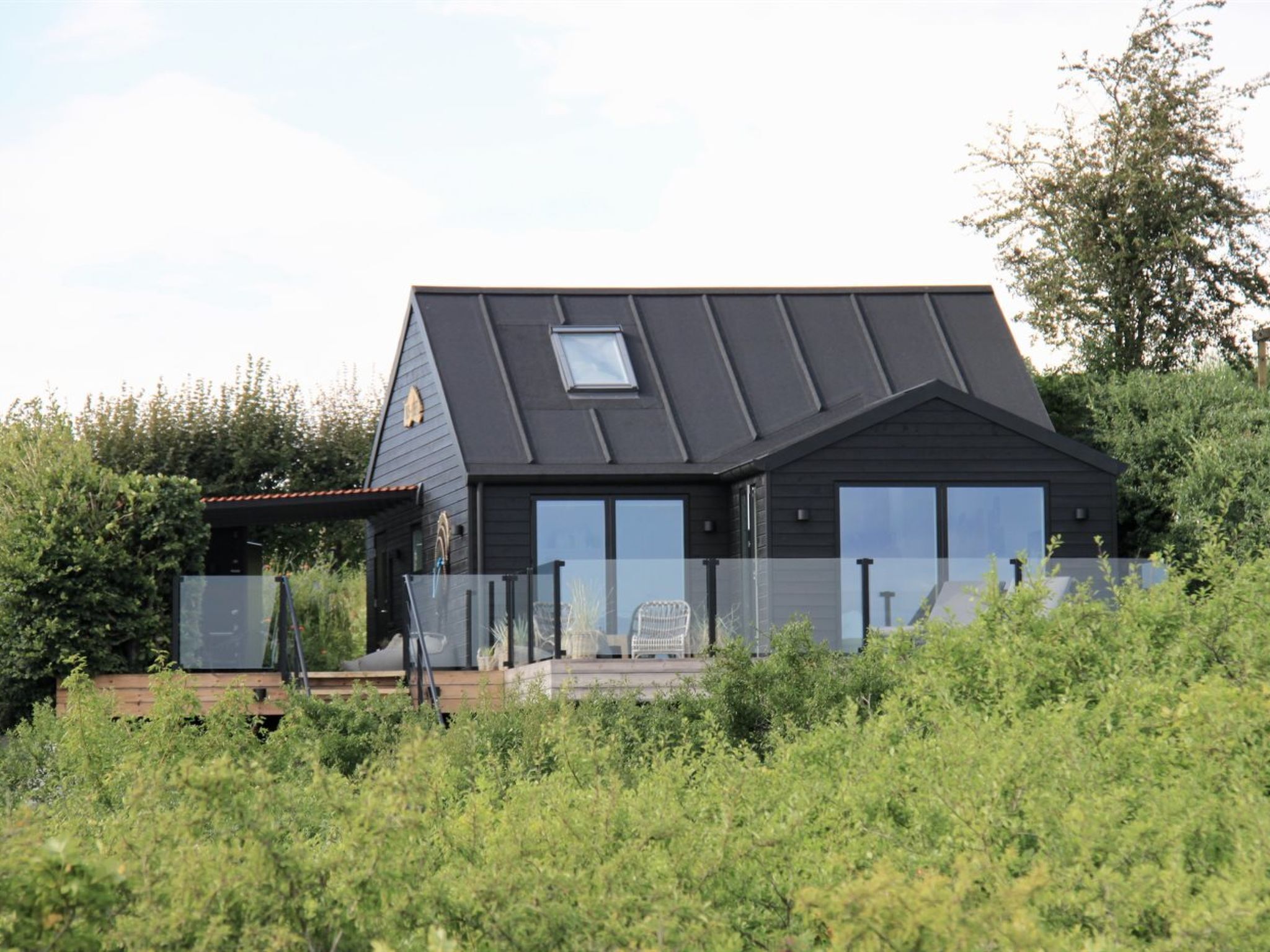 A modern house with a sloped roof, large windows, and a small balcony.