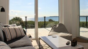 A modern living room with a large sliding glass door leading to a deck overlooking a body of water. - "Valia" - 20m from the sea by Interhome (Sønder Stenderup)