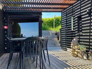 An outdoor patio with a table and chairs, a pergola, and a view of a garden. - "Valia" - 20m from the sea by Interhome (Sønder Stenderup)