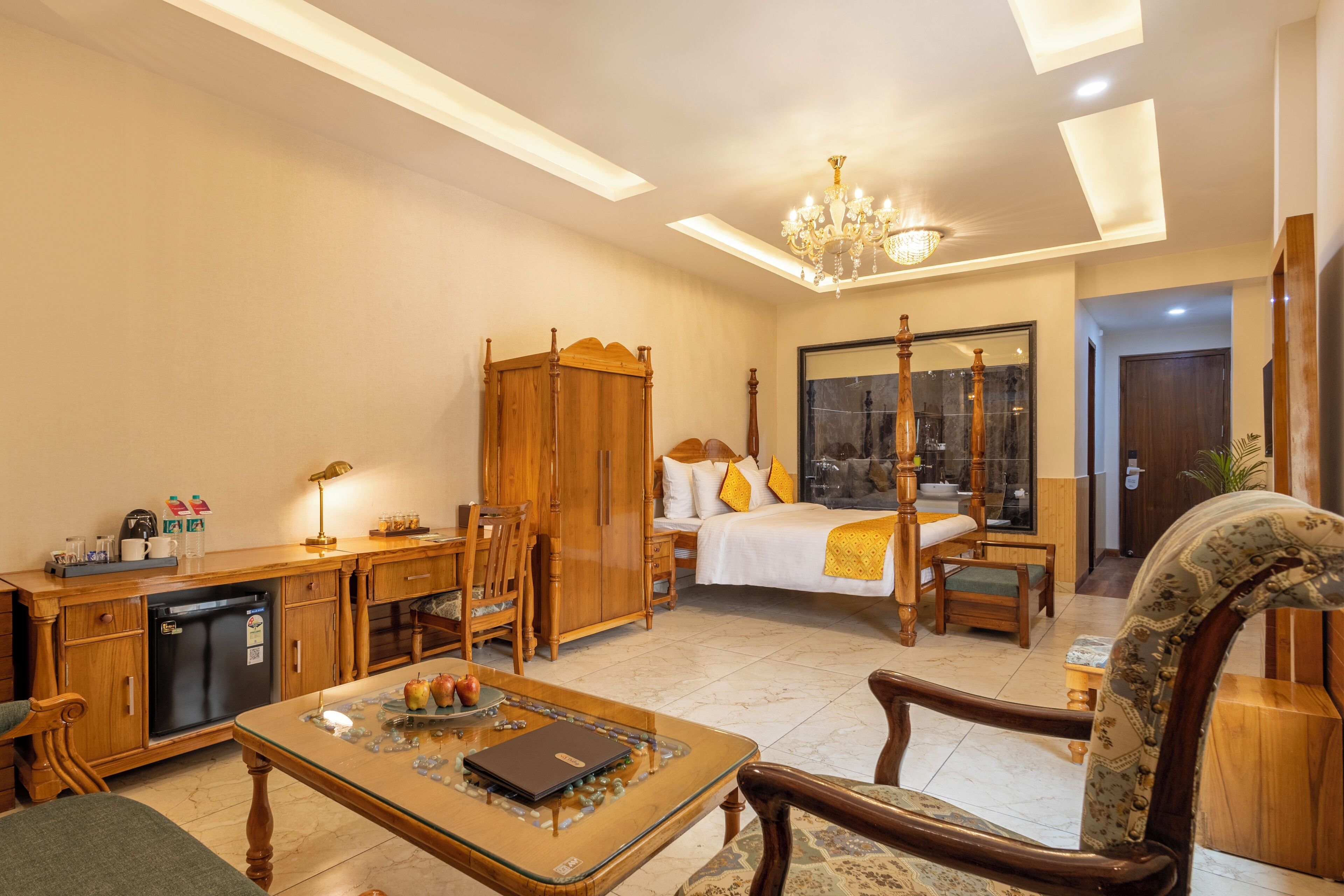 A hotel room with a bed, a desk, a wardrobe, a dining table, and a chandelier.