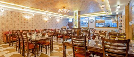 Ein Restaurant mit mehreren Tischen und Stühlen, Wandpapier mit Muster und einem geometrischen Fußboden.