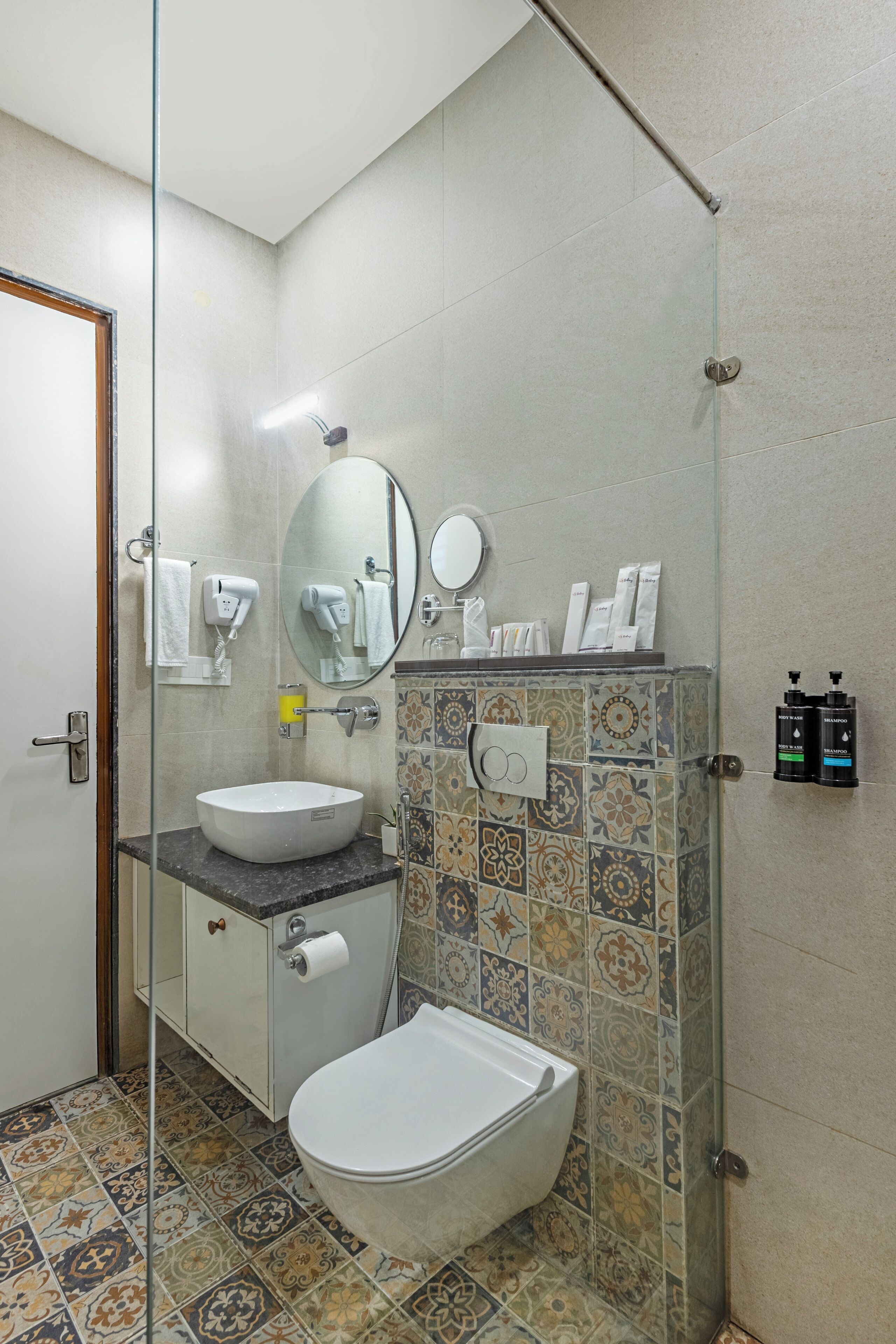 Une salle de bain avec une douche à parois de verre, un lavabo blanc, des toilettes et un miroir au-dessus du lavabo.