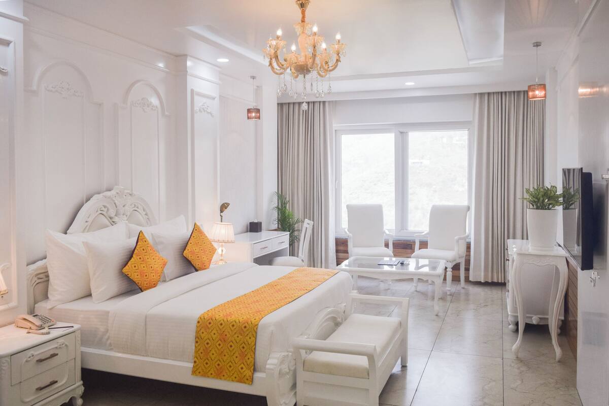 A spacious hotel room with a large bed, a sitting area with a coffee table, and a television on a stand.