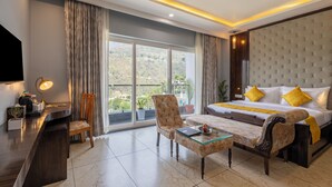 A hotel room with a large bed, a desk, a chair, and a glass coffee table. - Sterling Kastoori Rudraprayag (Jakholi)