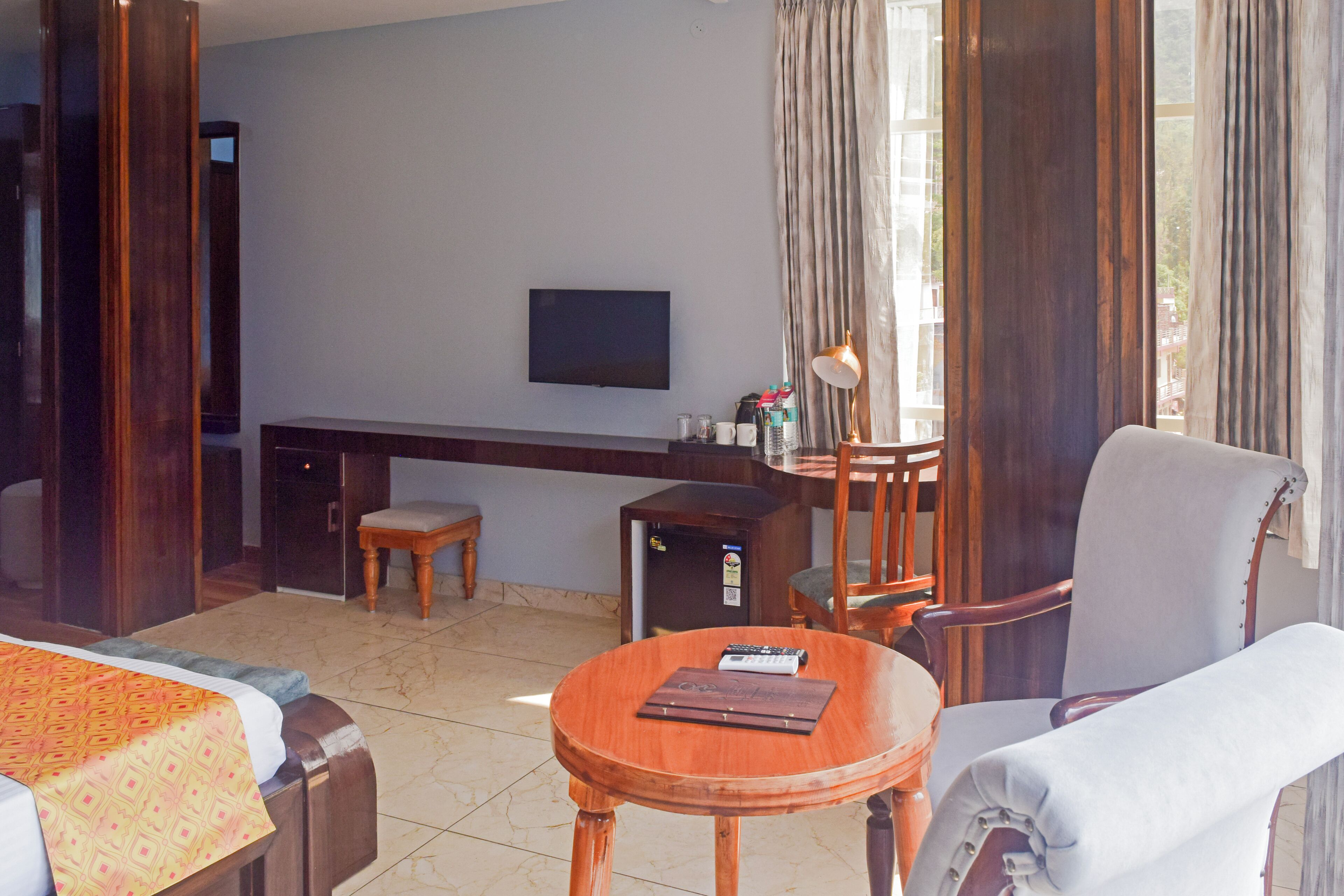 A hotel room with a bed, a desk, a chair, and a TV.