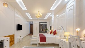 A modern hotel room with a bed, bedside tables, a TV, and a glass coffee table with apples. - Sterling Kastoori Rudraprayag (Jakholi)