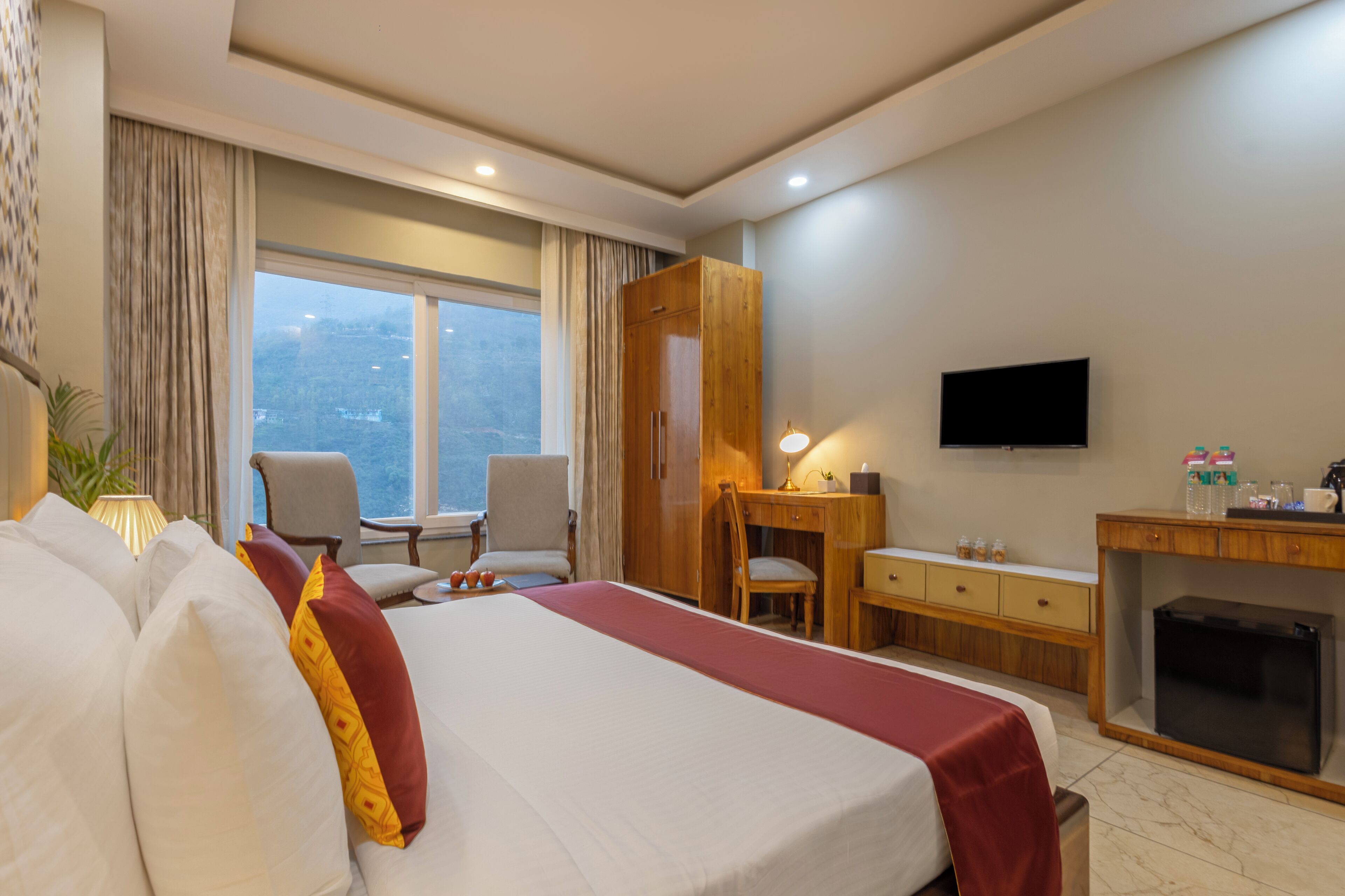 Une chambre d’hôtel avec un grand lit, un bureau, une chaise, une télévision et une vue sur la ville.