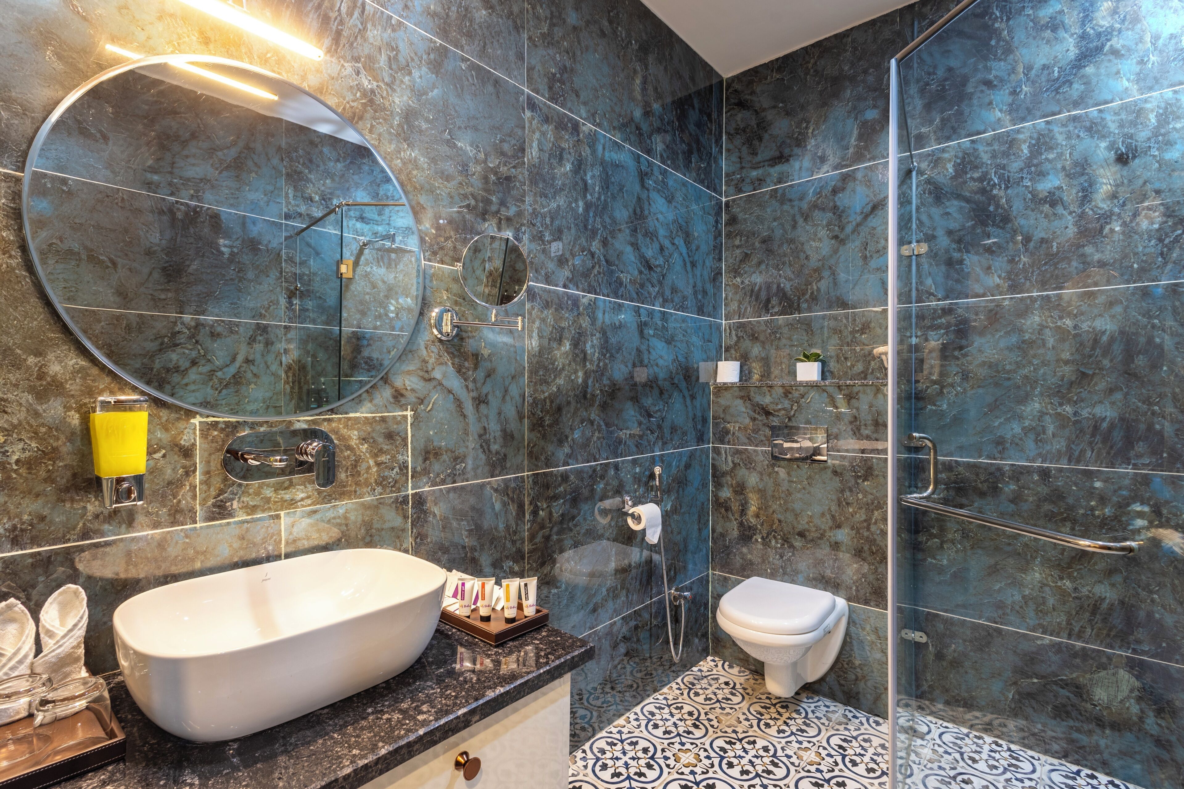 A modern bathroom with a freestanding bathtub, a round mirror, a toilet, and a shower area.