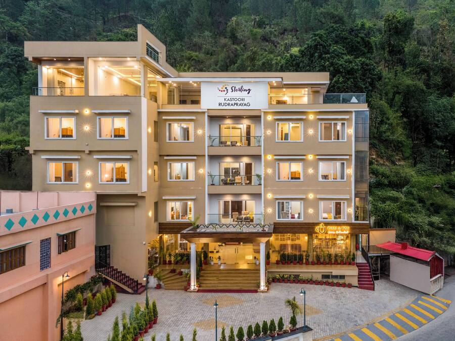 Un hotel de varios pisos con un diseño moderno, con balcones, una entrada central con zona cubierta y un cartel que indica el nombre y la ubicación.