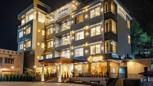 A multi-story hotel with illuminated signage, a well-lit entrance, and a staircase leading to the upper floors. - Sterling Kastoori Rudraprayag (Jakholi)