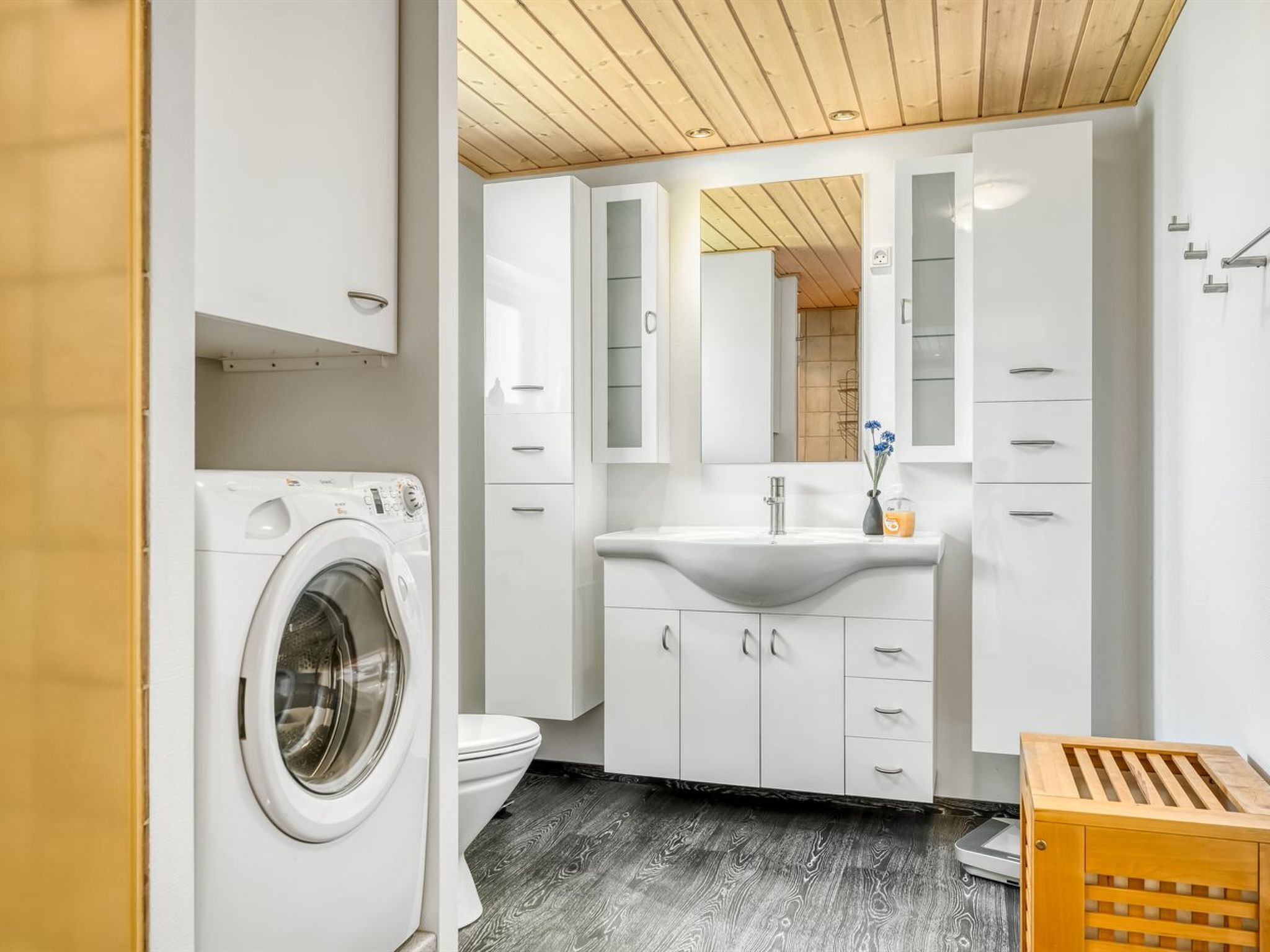 Une salle de bain moderne équipée d’un lave-linge, de toilettes et d ’un plancher en bois.