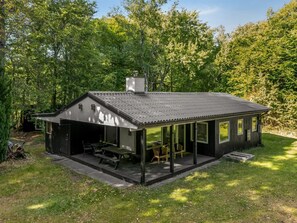 Uma cabana moderna com varanda coberta, garagem e chaminé.