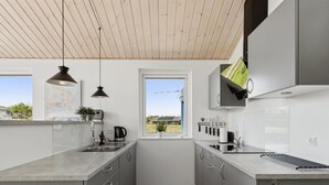 Une cuisine moderne avec des meubles de couleur grise, un plafond en bois et une fenêtre donnant sur l’extérieur.