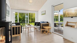 Un salon moderne avec une cheminée, un plancher en bois, un canapé, une table et un téléviseur fixé au mur.
