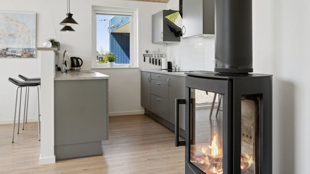 Une cuisine moderne dotée d’un îlot central, d’une cuisinière intégrée et d’une fenêtre donnant sur un immeuble bleu.
