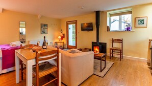 Un salón acogedor con chimenea, muebles de madera y un comedor con mesa para dos.