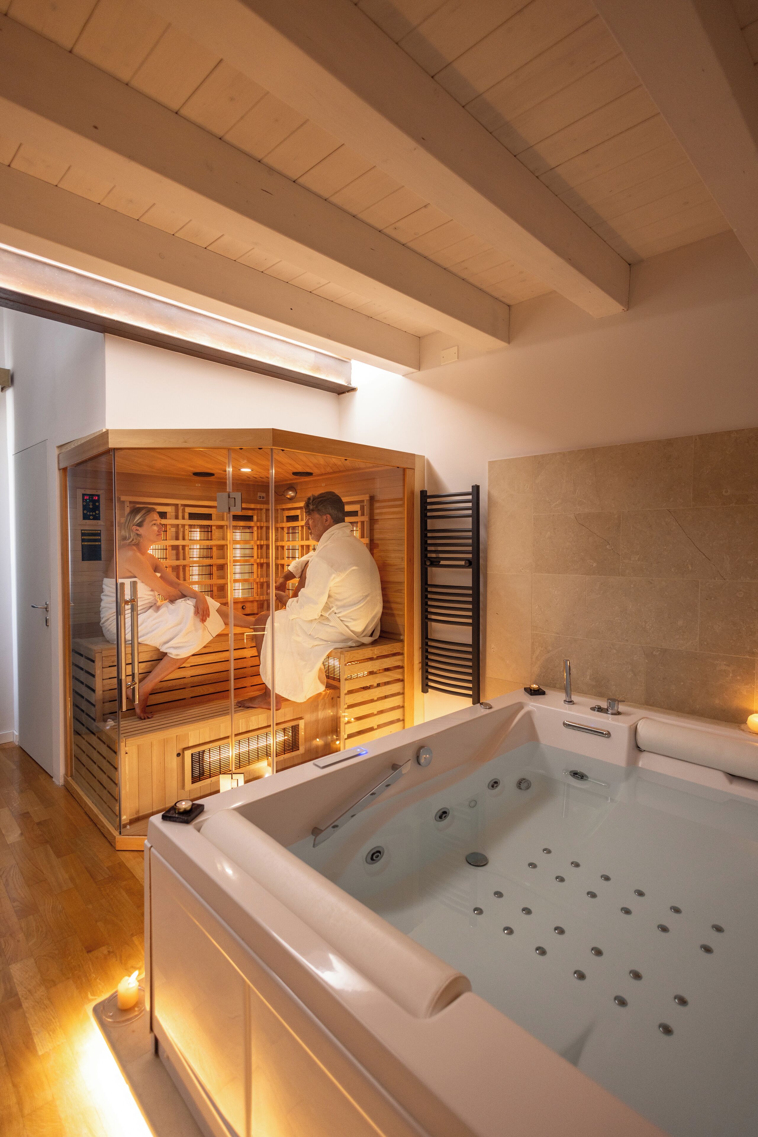 En sauna med to personer indeni, et stort badekar og et træloft.
