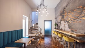 A modern restaurant with wooden flooring, a staircase, and a bar area with yellow stools. - Noto Boutique Hotel (Noto)