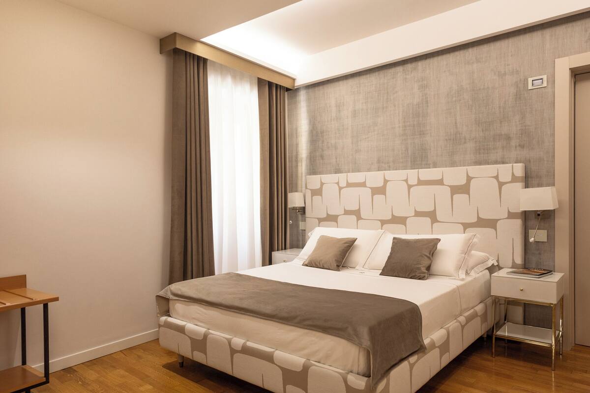 Un dormitorio moderno con una cama grande, suelo de madera, una mesita de noche y un escritorio.