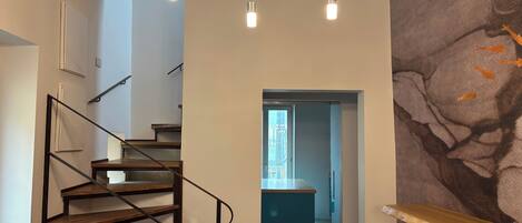 Um interior moderno com escada de madeira, área de cozinha e espaço para refeições.