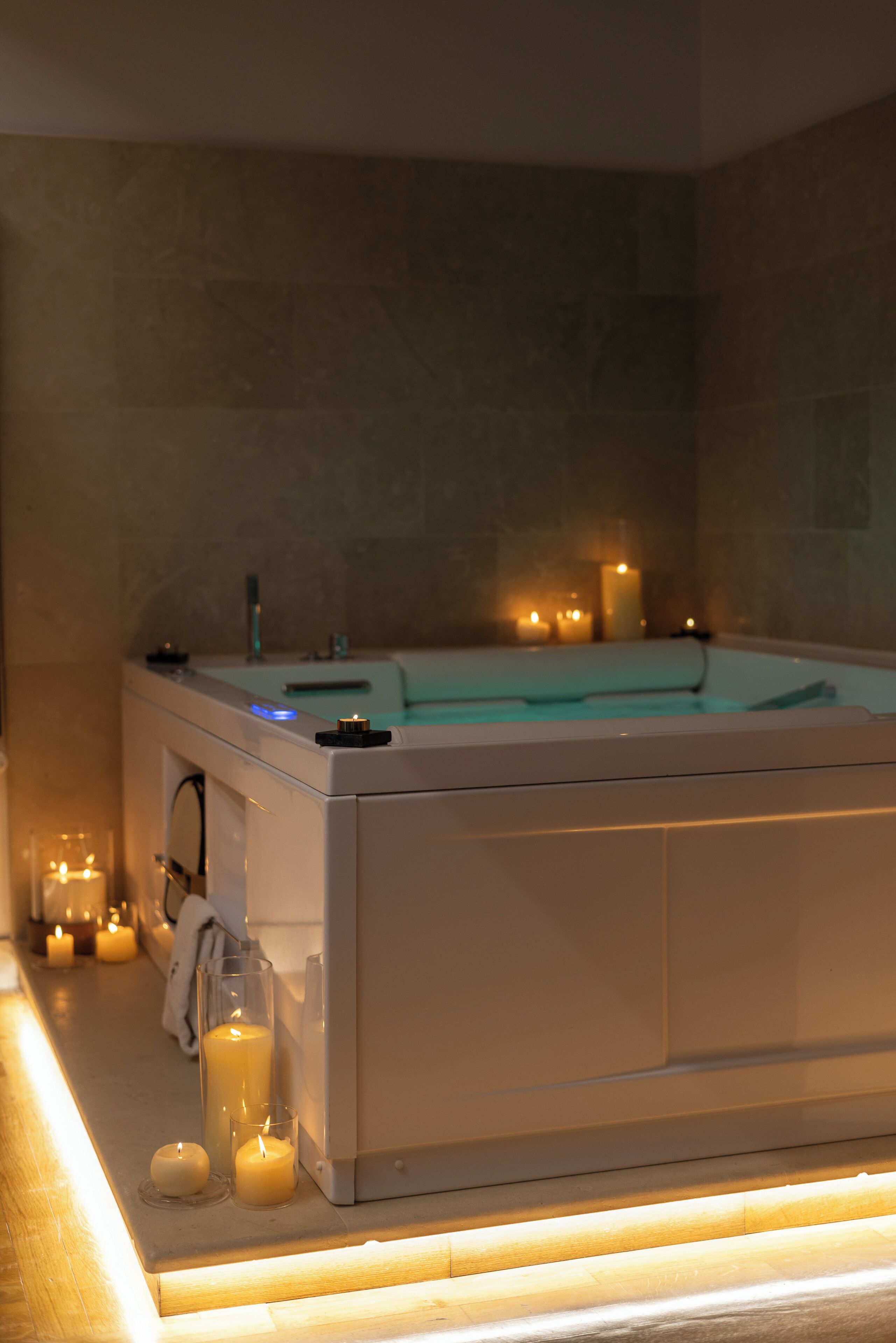 Un cuarto de spa con una bañera, velas y piso de madera.