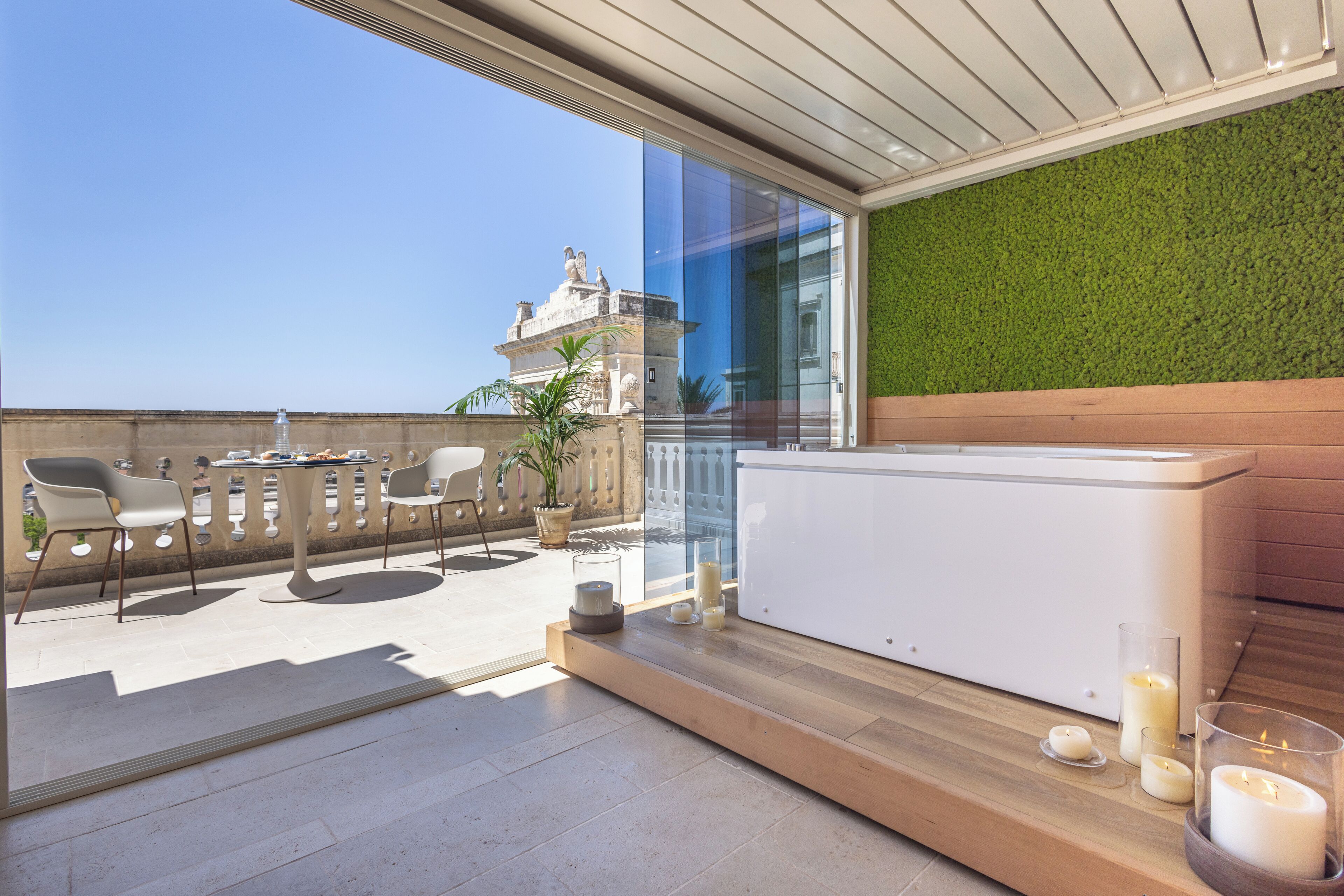 A modern outdoor terrace with a seating area, a water feature, and a view of a historical building.