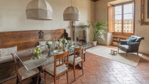 A dining area with a glass table, wooden chairs, and hanging pendant lights.