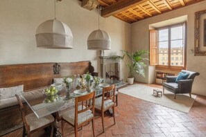 Un comedor con una mesa de vidrio, sillas de madera e iluminación colgante.
