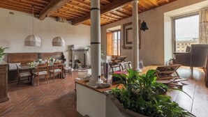 A spacious room with a wooden ceiling, a dining area with a table and chairs, and a large window providing natural light.