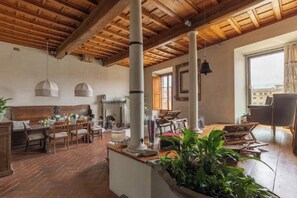 Una habitación amplia con techo de madera, un comedor con mesa y sillas, y un gran ventanal que proporciona luz natural.