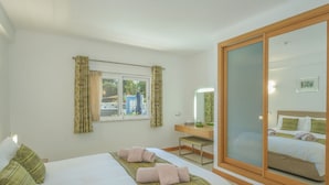 A hotel room with a bed, a desk, a mirror, and a sliding door. - Monte Zest Apt in Lagos (Lagos)