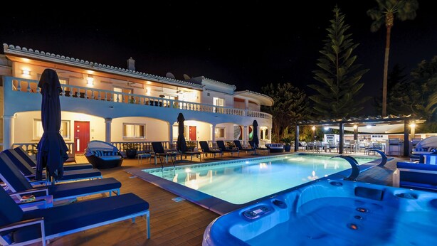 A pool area with lounge chairs and a hot tub, surrounded by a building with balconies and outdoor seating. - Monte Zest Apt in Lagos (Lagos)