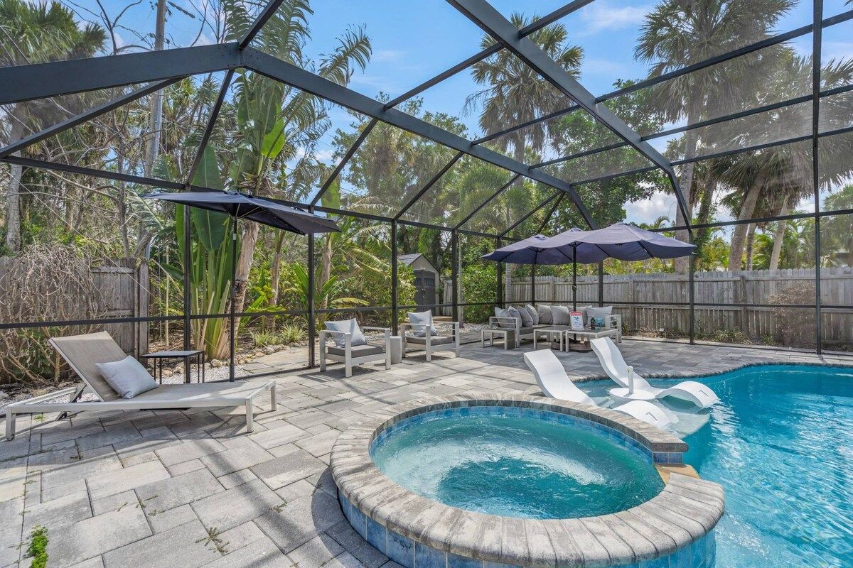 A pool area with lounge chairs, a hot tub, and umbrellas.