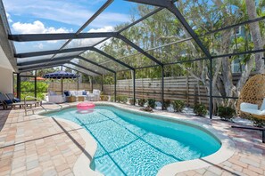 A covered swimming pool with lounge chairs and a wooden fence in the background. - Modern Coastal Retreat: 3BR, Private Pool, Walk to Beach, Luxe Outdoor Dining + NordicTrack Gym (Siesta Key)