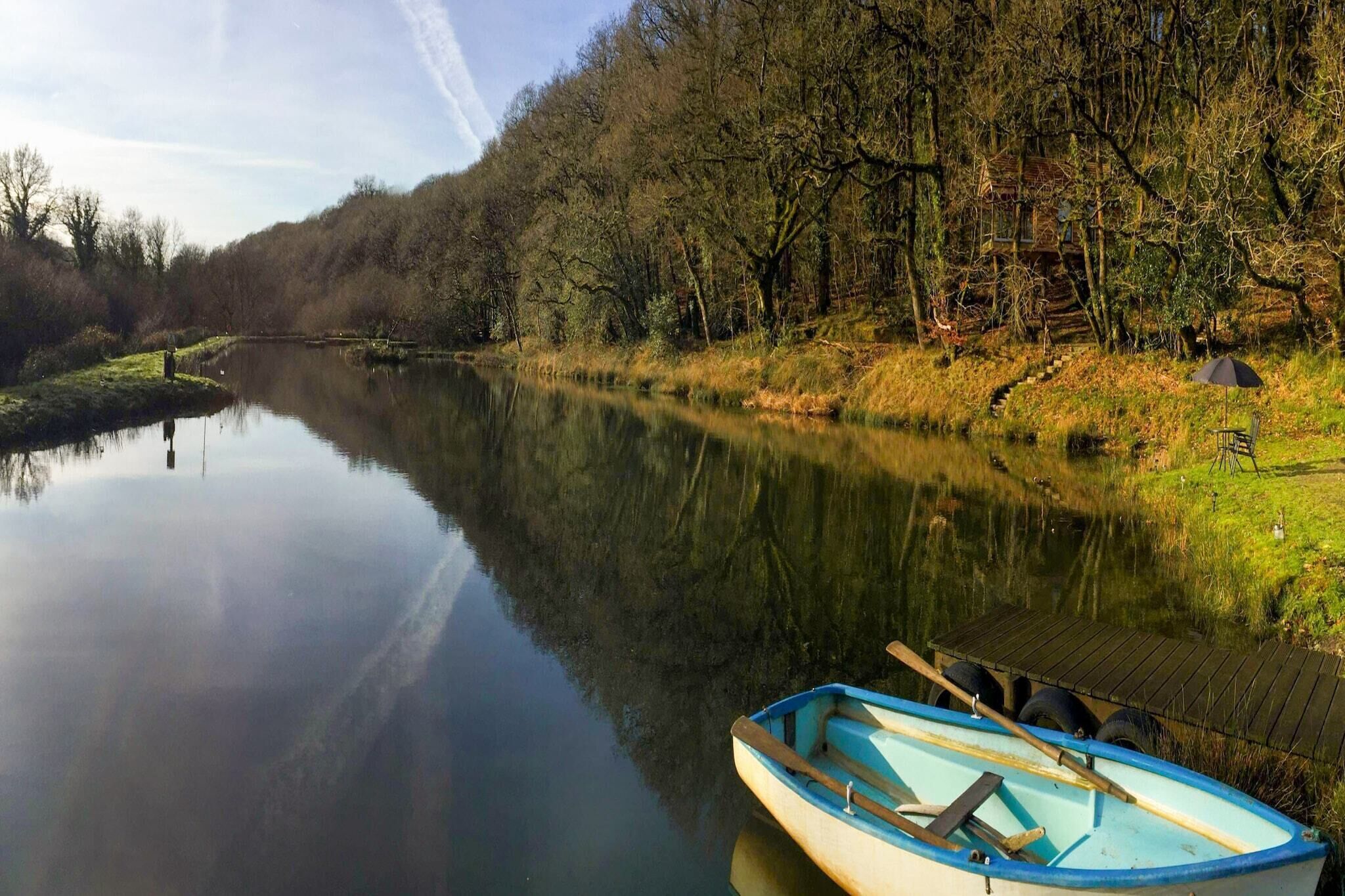 Un río tranquilo con un muelle de madera y un pequeño bote.