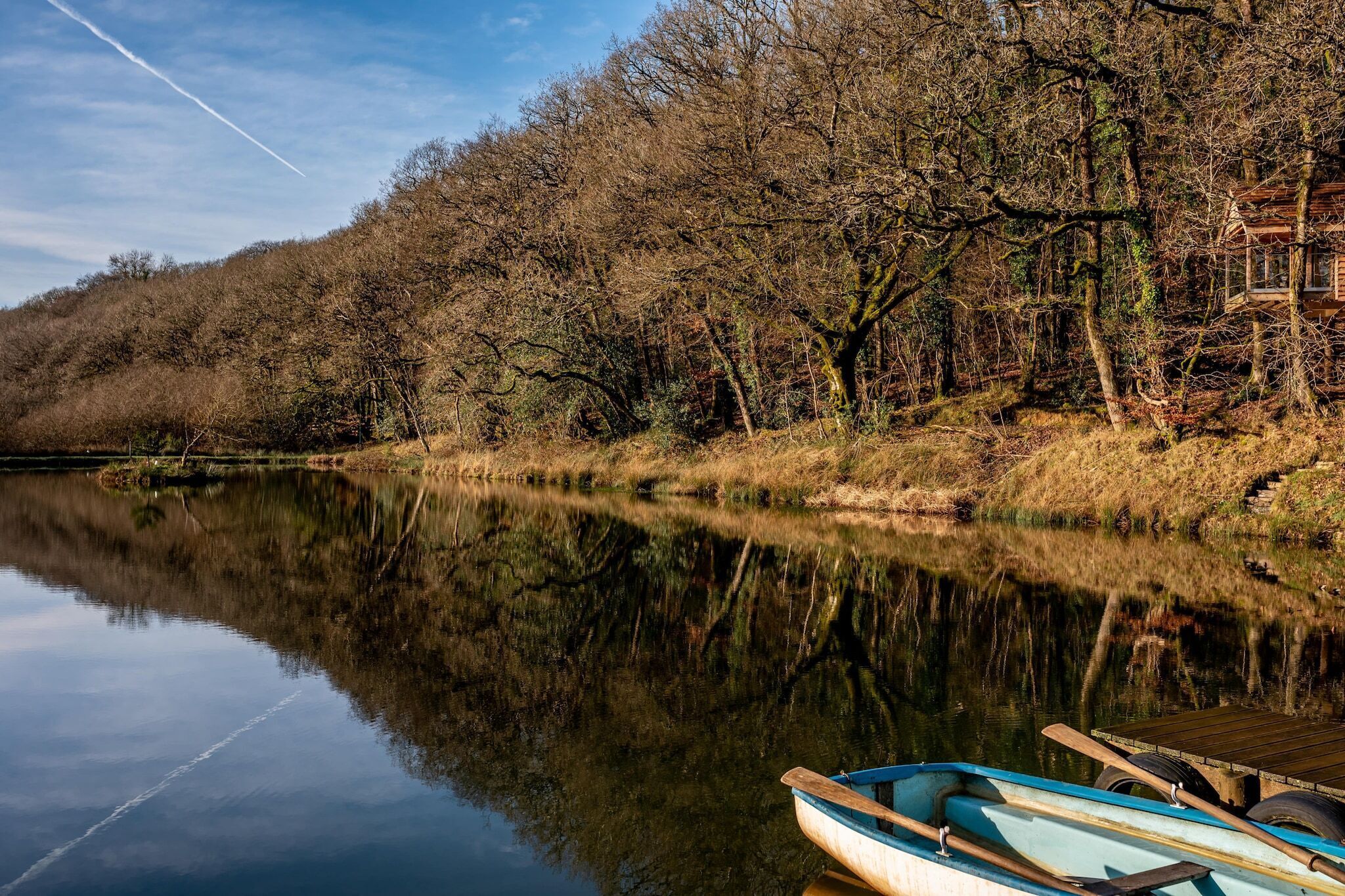 Een rustige rivier met een houten aanlegsteiger en een boot.