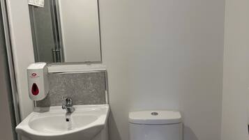 Un baño con lavamanos blanco, espejo y retrete.