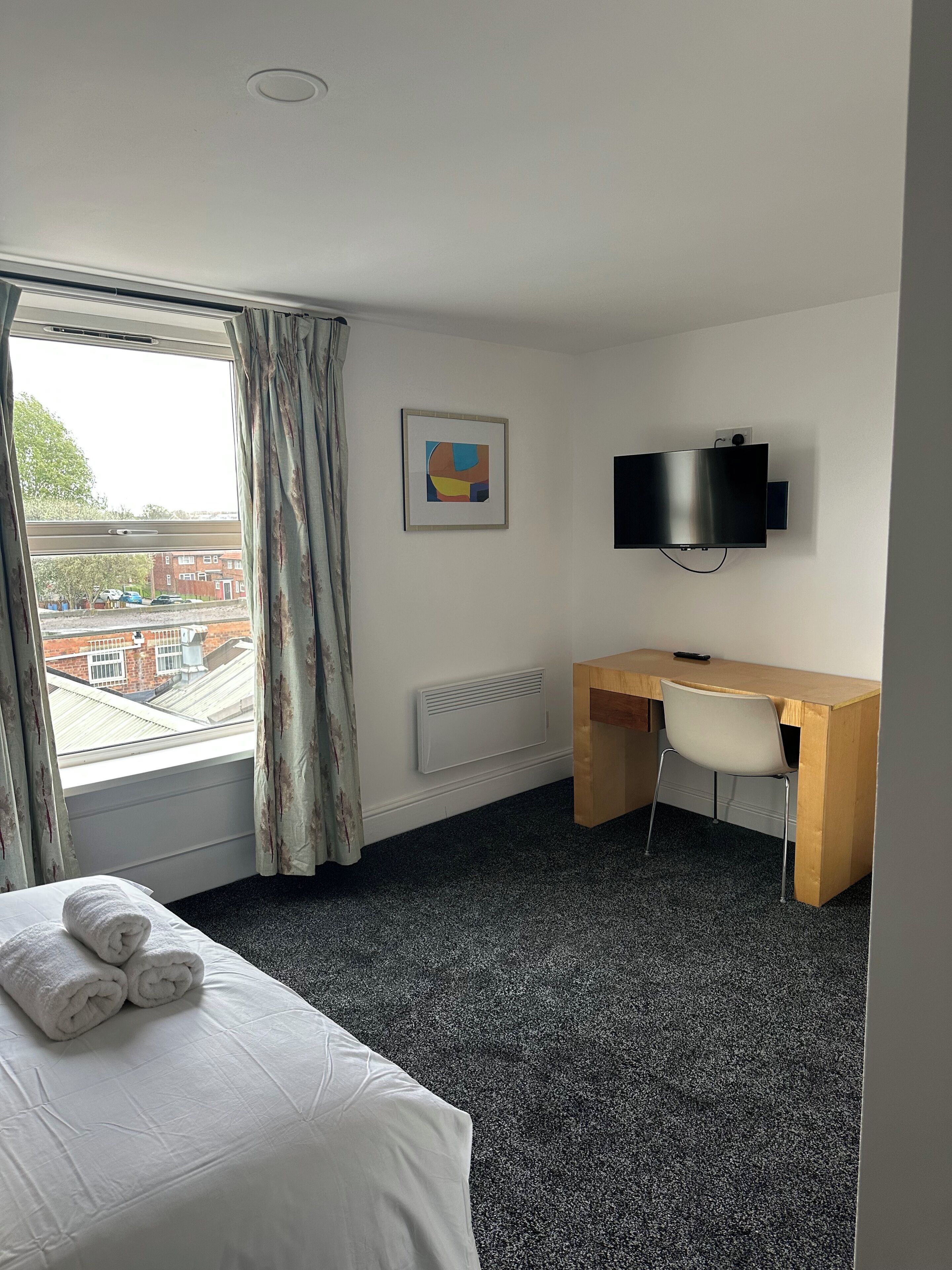 Une chambre d’hôtel équipée d’un lit, d’un bureau, d’une chaise, d’une télévision et d’une fenêtre avec des rideaux.