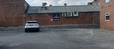 A parking lot with a white car parked in front of a building with a sign reading "Continental Hotel".