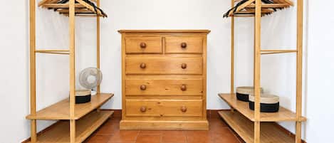 A wooden dresser with drawers and a fan on a shelf, flanked by wooden shelving units with baskets.
