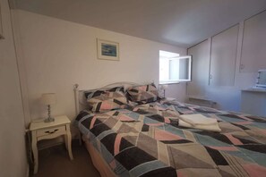 Une chambre à coucher avec un lit, une table de chevet, une fenêtre et une armoire.
