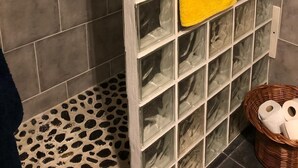 A bathroom with a tiled floor, a glass shower enclosure, and a yellow towel hanging on the wall. - Imperio vert adventure with a view (Tabua)