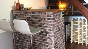 A kitchen area with a brick island counter, two white bar stools, a wooden spoon, a bamboo roll, and a staircase. - Imperio vert adventure with a view (Tabua)