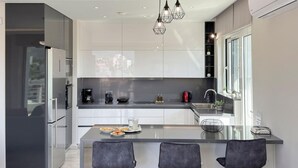 A modern kitchen with a central island, stainless steel appliances, and pendant lighting. - Ardians Home, Be on Holidays (Chania)