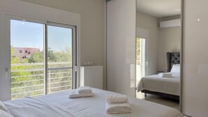A bedroom with a large bed, a smaller bed, and a sliding glass door leading to a balcony. - Ardians Home, Be on Holidays (Chania)