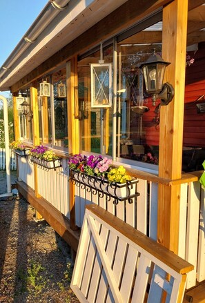 A wooden porch with flower planters and hanging lanterns. - Rural villa with large patios, jacuzzi and quiet location near Östersund (Jämtlands län)