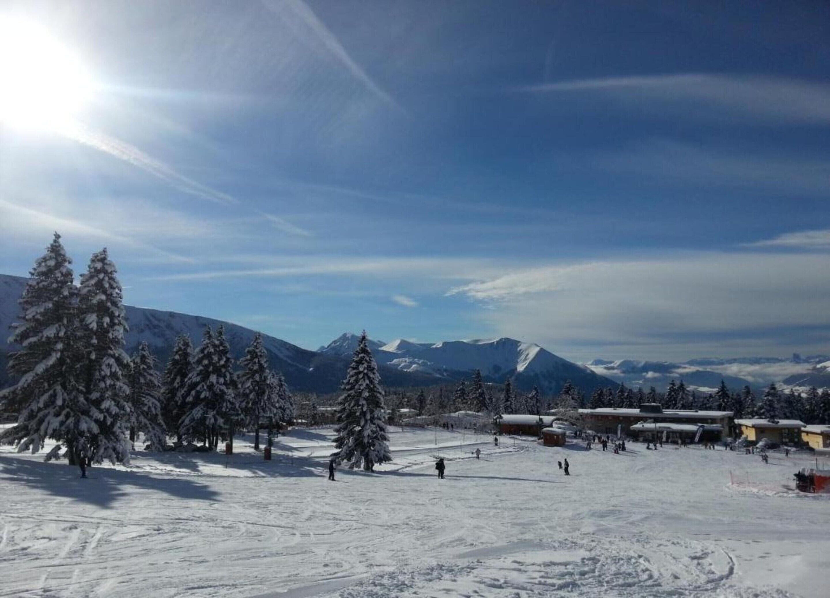 Een besneeuwd landschap met een skigebied, inclusief skipistes en gebouwen.
