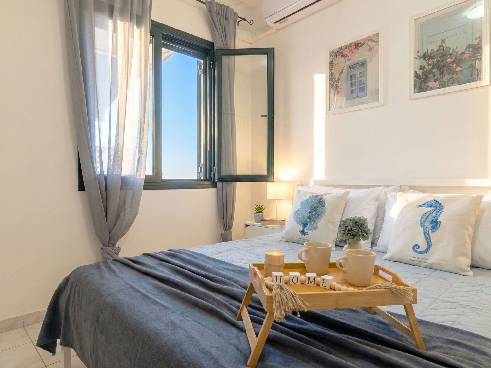 Een slaapkamer met een bed, een nachtkastje met een lamp, een dienblad met mokken en een plant, en een raam met gordijnen.