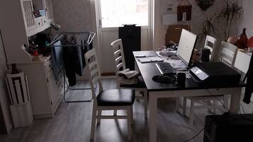 Een goed verlichte keuken met een eettafel, stoelen en een hangende lamp.