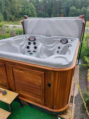 A hot tub with a wooden exterior and a cushioned top.